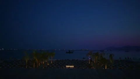 View of multiple, empty loungers on the beach at night in Cannes, France Stock Footage 309680893