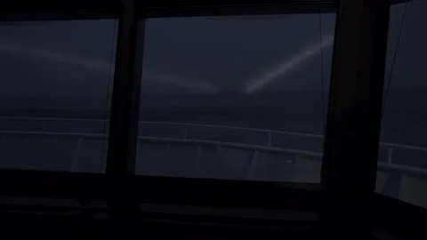 View from navigation bridge of ship. Searchlight beams shine forward. Pitching Stock Footage 257067459