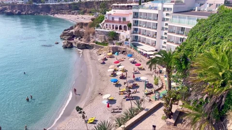 View of the Nerja beach with sunbeds and sunshades and people taking a swim. Stock Footage 238076081