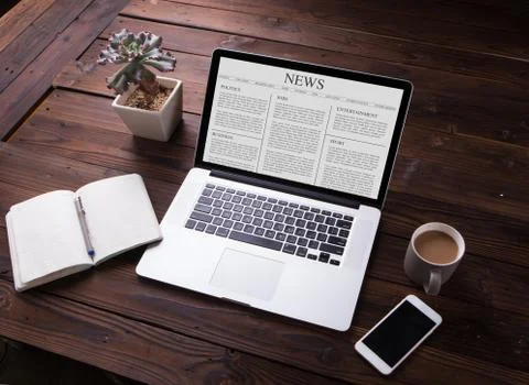 View of News article on the laptop / computer screen with smartphone Stock Photos