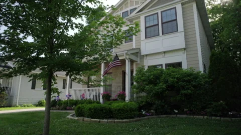 View of nice house in the suburbs with an American flag flying in the Stock Footage 197310296