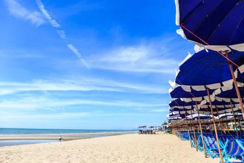 View of nice tropical empty sandy beach with umbrellas and beach beds Stock Photos