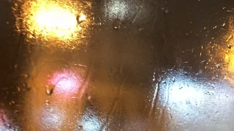 View of the night city lights through a wet car window during rain Stock Footage 119945320