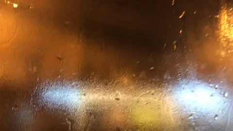 View of the night city lights through a wet car window during rain Stock Footage 119945321
