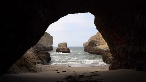 View of the ocean and cape with rocks through a cave in the rock in California Stock Footage 154354554