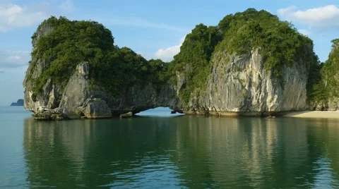 View of the ocean and small limestone cliff island with white sand beach Stock Footage 61496215