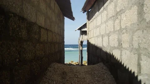 View of the ocean between small brick homes in Bali Indonesia Stock Footage 145031455