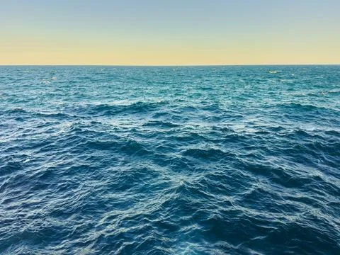 View of the ocean during sunset with waves reflecting light and the horizon.. Stock Photos
