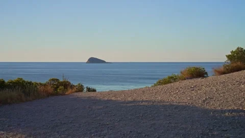 View of the ocean from the shore at sunset showing the distant island and g.. Stock Footage 340190813