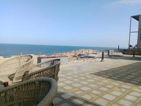 View of the ocean from a tiled patio with wicker furniture Stock Photos