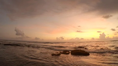 View on ocean with waves and rocks and yellow red amazing sunset Stock Footage 128959065