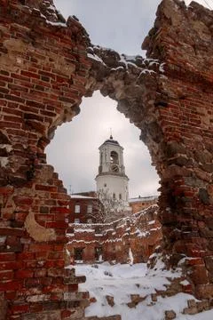 View of old Clock Tower through ruined brick wall. Belfry of Vyborg Cathedral Stock Photos