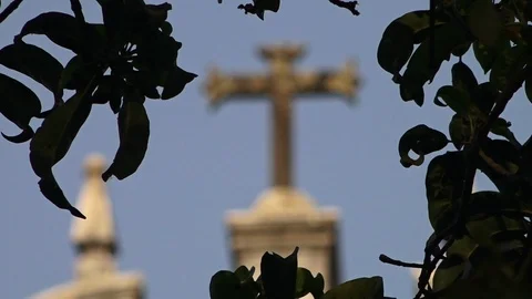 A view of an old cross seen through the branches of a tree Stock Footage 94698169