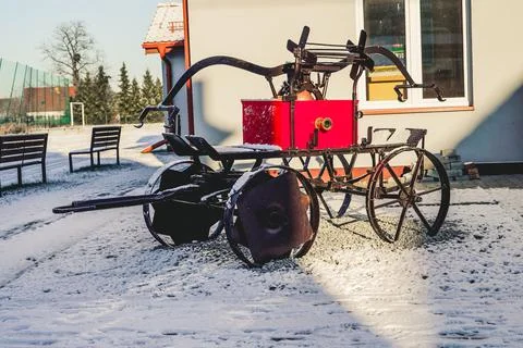 View of an old fire engine in snow land beside a white building on a sunny winte Stock Photos