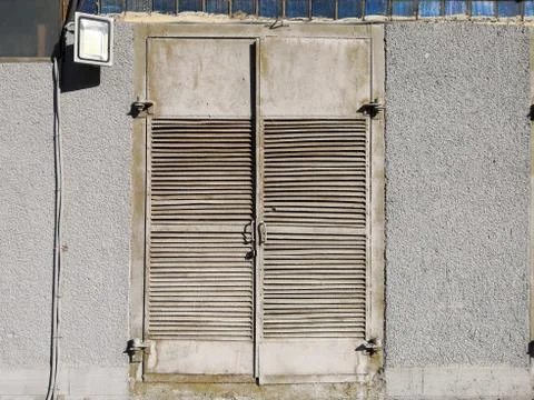 View of the old gray double-leaf metal door of an electric panel in the concr Stock Photos