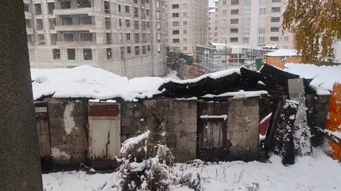 View of old, ruined stone structures covered in thick white snow, with modern 動画素材 333240902