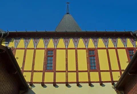 View on old style yellow wall with two windows and square tower on a building Stock Photos