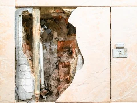 View of old water pipe through broken ceramic tile Stock Photos
