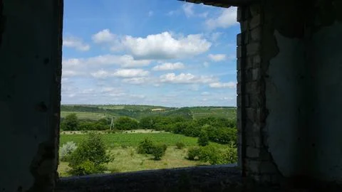 View from the old window of green meadows and blue sky with white clouds Stock Photos