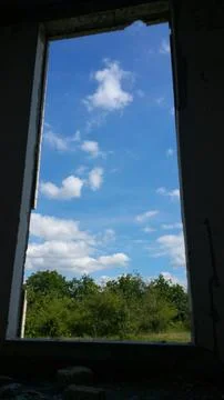View from the old window of green meadows and blue sky with white clouds Stock Photos