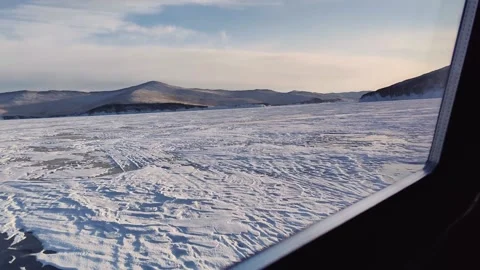 View of Olkhon Island from window of hovercraft rushes across frozen lake Baikal Stock Footage 230212047