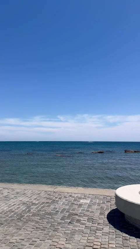 View of the open blue sea looking right from a coastal promenade rest stop Stock Footage 337366689
