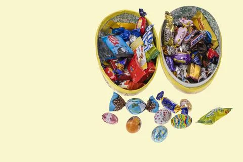 View of an open gift Easter egg with candies inside isolated. Stock Photos