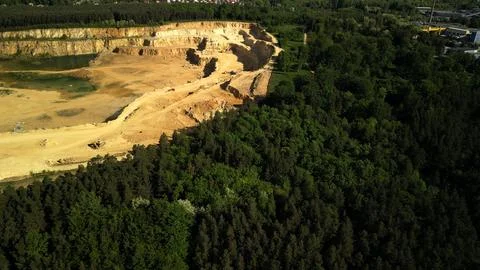 View of Open-Pit Dolomite Quarry from Forest with Flooded Area and Industrial Bu Stock Photos