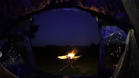 View from open tent at fire burning late evening camping Stock Footage 145985832