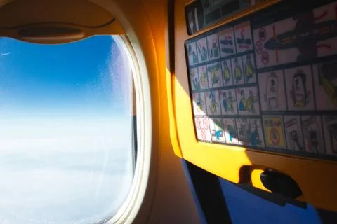 View of open window and back of passenger seat on a plane in the air Stock Photos