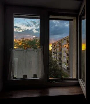 View from an open window of facade of typical Soviet high-rise in the sunset Stock Photos