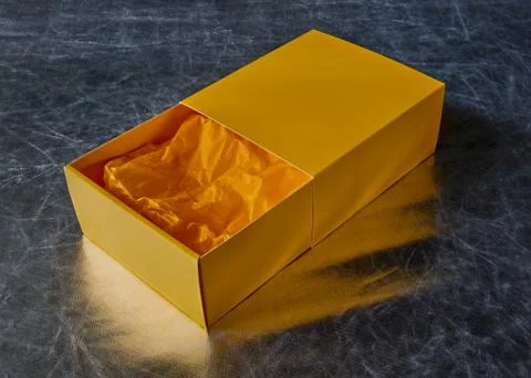 View of an open yellow gift box with packaging paper inside Stock Photos