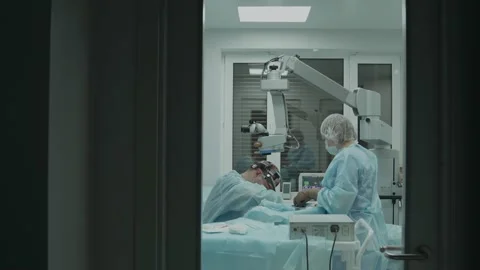 View of the operating room through a transparent door. surgeons perform the Stock Footage 143458470