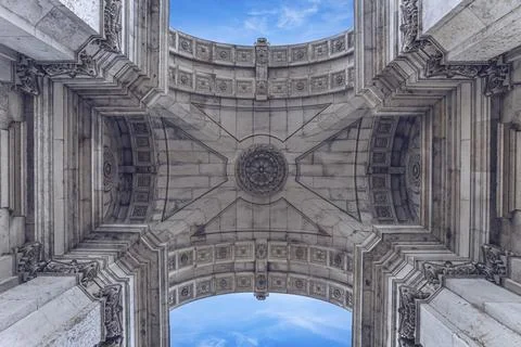 View of ornate stone arch pattern with symmetrical details and clear blue sky in Stock Photos