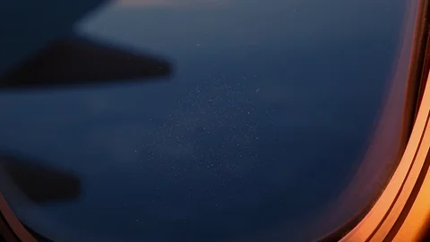 A view out of an aircraft window looking over the wing at sunset. Видео 96547090