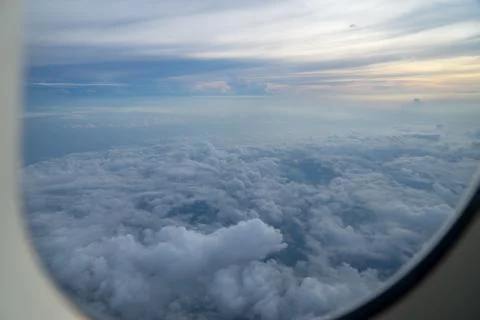 View out of airplane window with clouds at sunset. Stock Photos