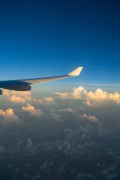 View out of airplane window with clouds at sunset and airplane wing. Foto stock