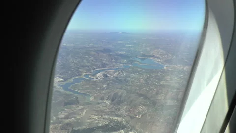 View Out of Airplane Window of Lake and Rocky Terrain Stock Footage 237807916
