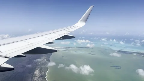 View out airplane window wing of tropical Caribbean Mexico coast blue sky clouds Vidéo 194173318