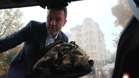 View out of the car boot on middle aged man hurrying up, putting his soldiers Stock Footage 105249422