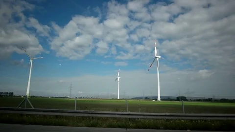 View out of car window passing by windmill farm with wind turbines. Sustainable Stock Footage 84884797