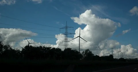 View out of car window passing by windmill farm with wind turbines. Sustainable Stock Footage 84886019