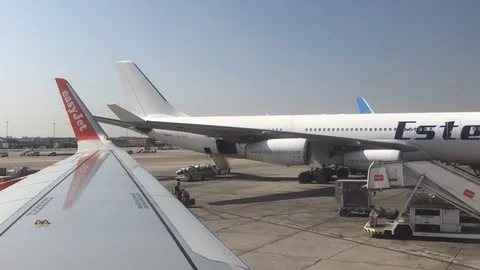 View out of commercial plane window as luggage buggy drives across runway Stock Footage 112126226