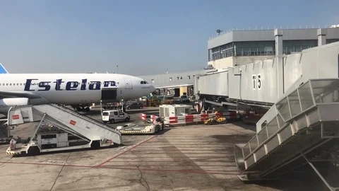 View out of commerical plane window of terminal and a plane being loaded Stock Footage 112126162