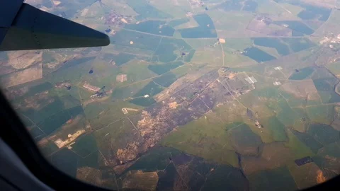 View out of plane window over green patchwork landscape fields &amp; green Video stock 101903384
