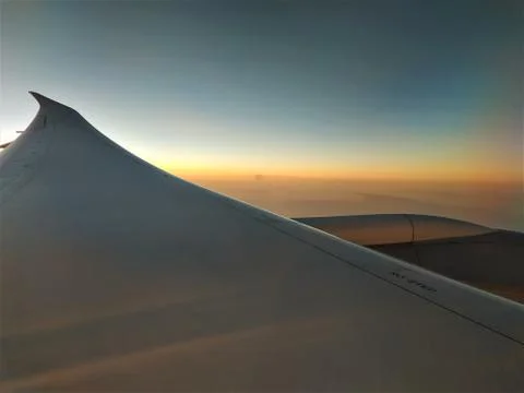 View out of plane window over wing into sunset Stock Photos