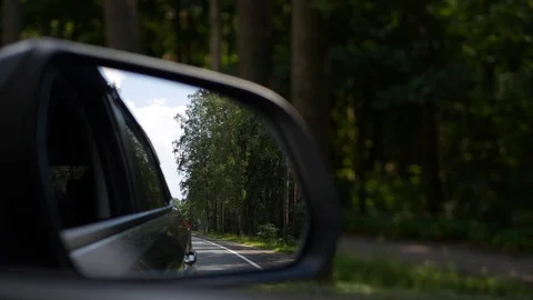 View out the rearview mirror as car drives on country road. 4K Stock Footage 101784426