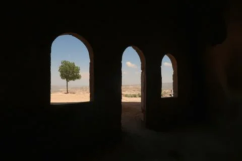 View out of some windows of the Uchisar Castle, Kalesi onto a tree and the .. Stock Photos