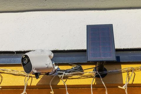 View of outdoor security camera and solar panel covered with snow on villa wall. Stock Photos