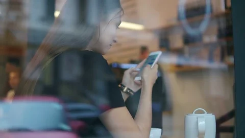 View from the outside of a concentrated young lady with long hair messaging Stock Footage 79527850
